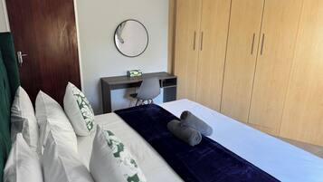 A bedroom with a bed, a desk, a chair, and a wardrobe.