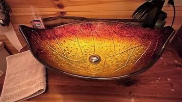 A wooden countertop with a decorative glass sink.