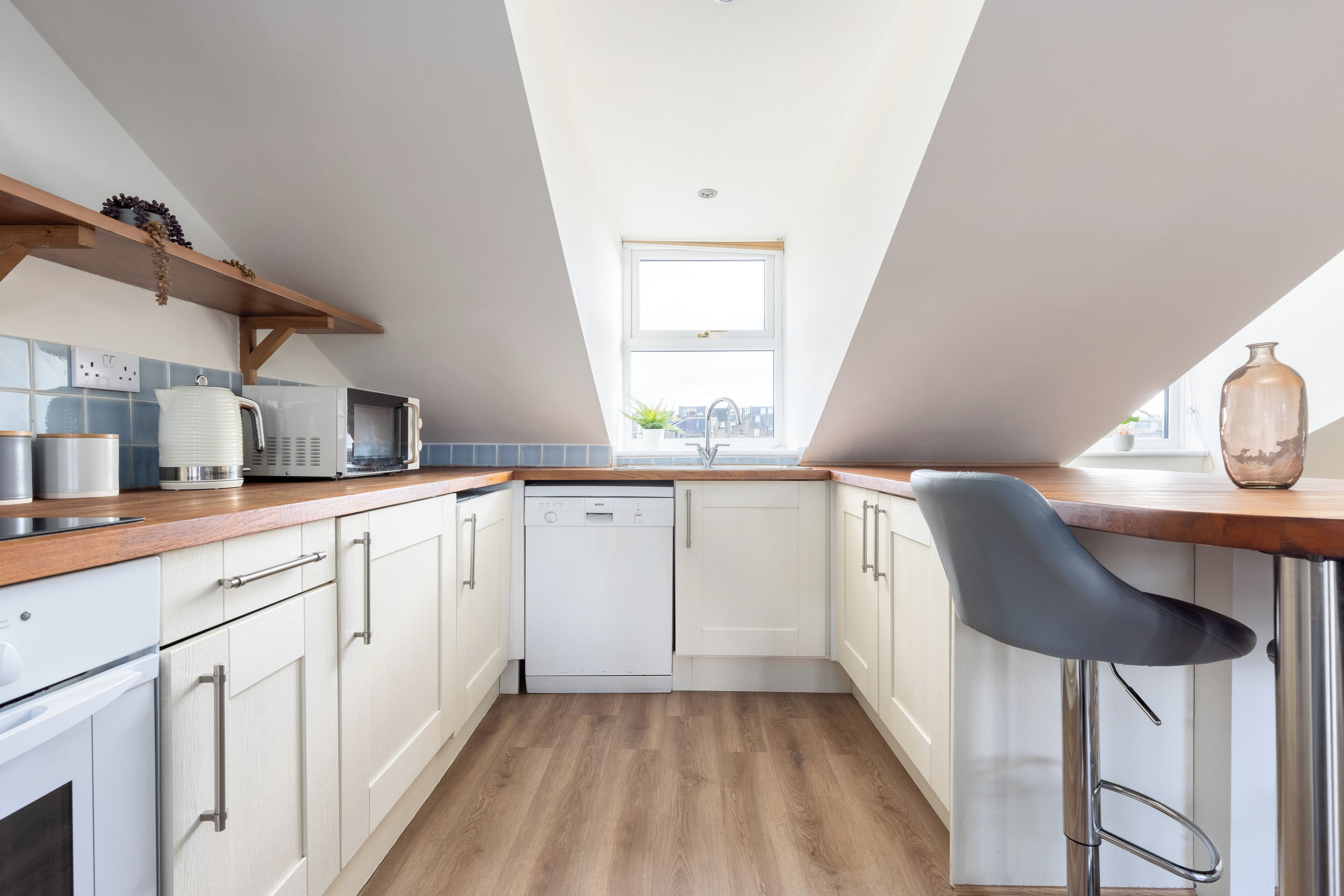Une cuisine moderne avec des meubles blancs, un lave-vaisselle et un plan de travail en bois.
