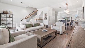 A spacious living room with a staircase, a dining area, and a kitchen.