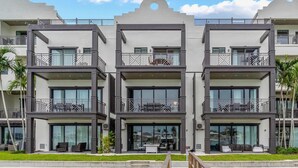 A modern multi-story hotel with balconies, large windows, and a pool area.