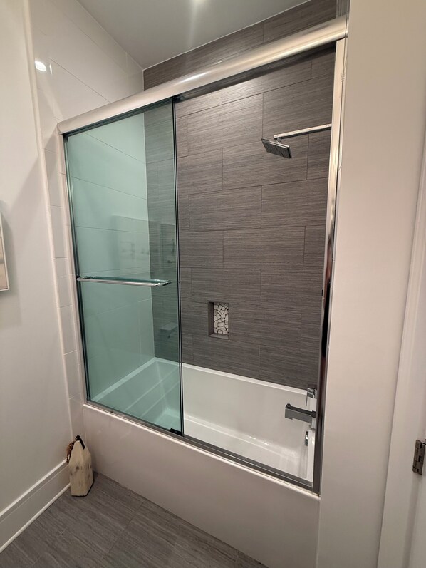 Un baño moderno con cabina de ducha de vidrio, suelo de baldosas e instalación de lavabo empotrada.