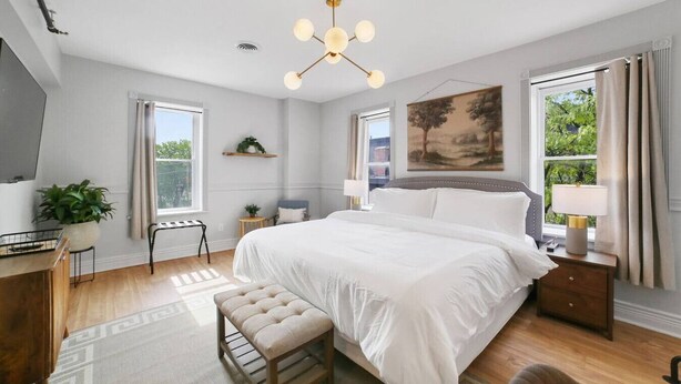 A bedroom with a large bed, bedside lamps, a desk, a chair, and a window with curtains. - Downtown Boutique Comfort w/ Style- Otter Suite (Saint Charles)