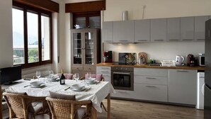 Una cocina moderna con armarios grises, una mesa de comedor para cuatro personas y vistas al exterior a través de ventanas amplias.