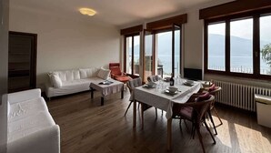 Amplia sala de estar con mesa de comedor, asientos y vista al mar.