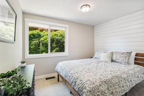 Een slaapkamer met een bed, een raam, een bureau en een potplant.