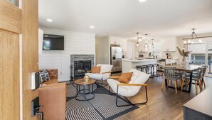 Una sala de estar moderna con chimenea, paredes blancas y un comedor con mesa y sillas de madera.