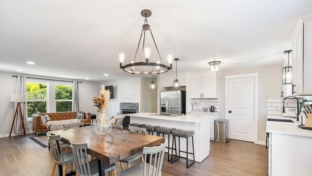 Una cocina amplia con una isla central, piso de madera y una lámpara moderna.