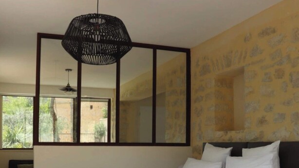 Une chambre à coucher avec un grand lit, un miroir et un luminaire suspendu.
