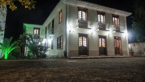 Um edifício de dois andares com várias varandas e janelas iluminadas à noite.