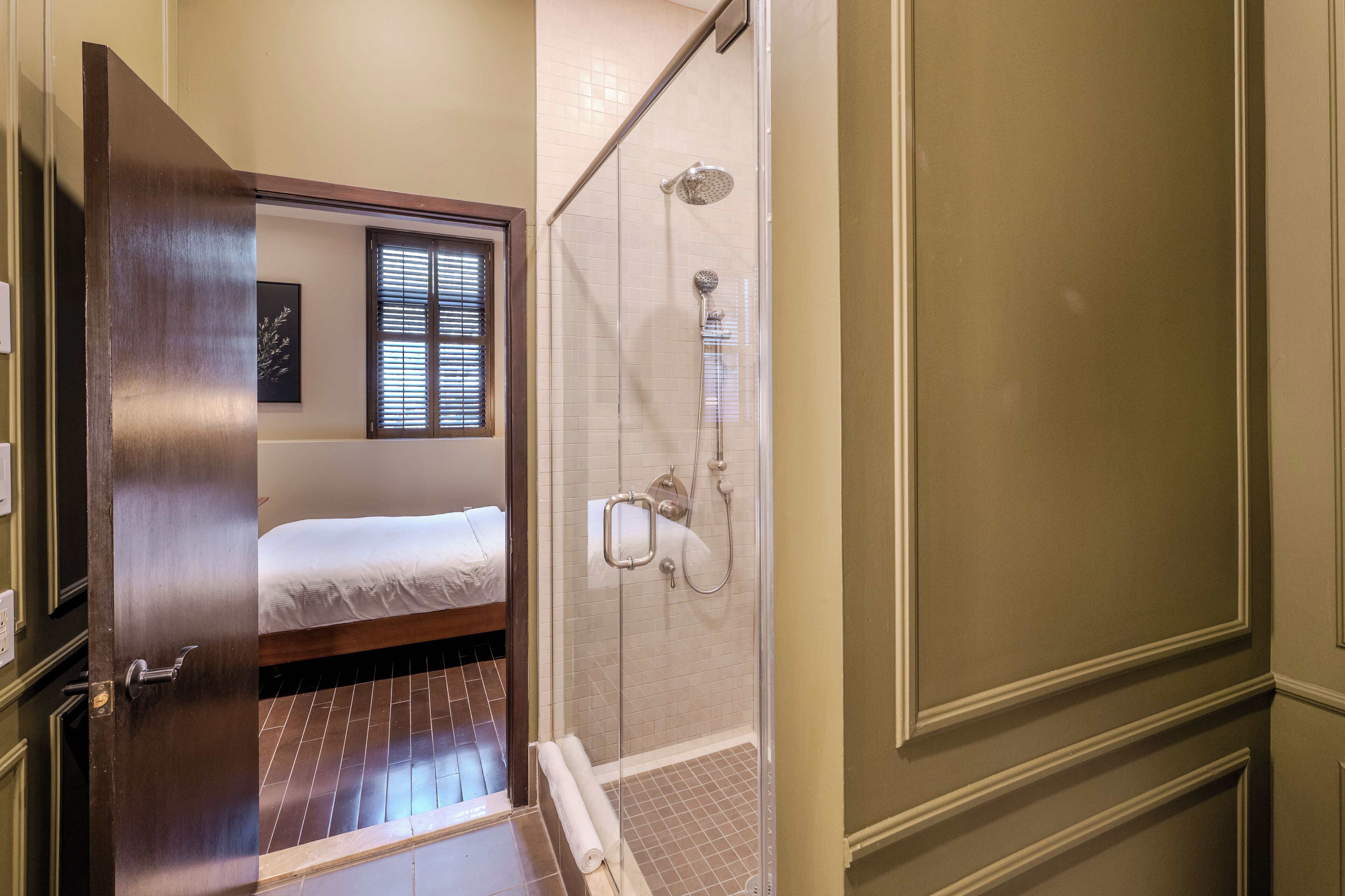 Ein Hotelzimmer mit einem Bett, einer Dusche und einer Holztür.