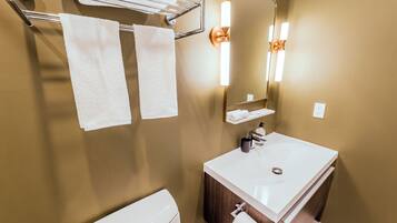 A bathroom with a white sink, a mirror, a towel rack with two towels, and a toilet.