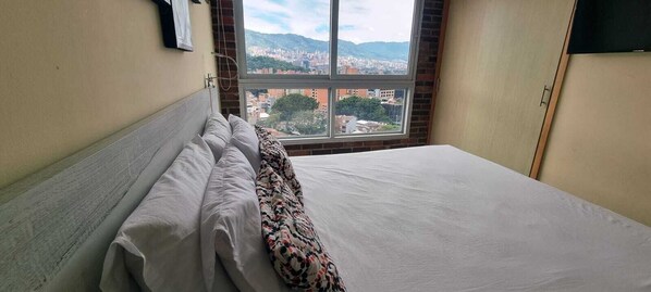 A hotel room with a bed, a window with a city view, and a wardrobe. - Laureles elegant Spring City Treat  (Medellín)