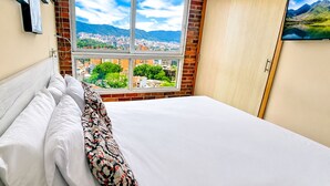 Una habitación de hotel con una cama, una ventana y vistas a la ciudad, además de una puerta.
