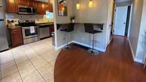 Una cucina moderna con mobili in legno, elettrodomestici in acciaio inossidabile e un'area bar con sgabelli.