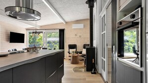 A modern kitchen with a large island, a built-in stove, and a dining area with a table and chairs. - Beautiful Home In Ebeltoft With Sauna (Ebeltoft)