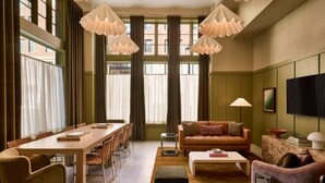 Ein modernes Wohnzimmer mit Esstisch aus Holz, einer Ledersofa und einem Fernseher an der Wand.