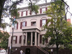 A two-story building with a central entrance flanked by columns, a brick facade, and a tree in the foreground. - City Access + Bike Rentals, Pool & Pet-Friendly (Savannah)