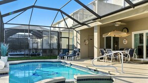 A pool area with a glass enclosure, lounge chairs, and a ceiling fan. - 5 Bedroom Pool Home in Gated Community Near Disney (Kissimmee)