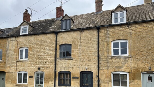 A row of terraced houses with stone walls, multiple windows, and doors. - Elm Cottage (Moreton-in-Marsh)