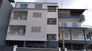 A multi-story residential building with balconies, a gated entrance, and a visible stairway. - Casa de nonoiluzia (Tarrafal)