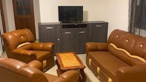 A living room with a sofa set, a coffee table, and a TV on a cabinet. - Casa de nonoiluzia (Tarrafal)
