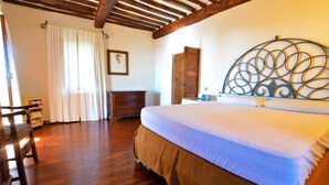 A bedroom with a wooden bed, a metal headboard, a wooden wardrobe, a wooden dresser, and a chair.