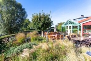A garden with outdoor seating, a glass conservatory, and a variety of plants. - Hajv Hotel Restaurant De Lepelaar (Lelystad)
