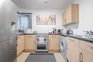 A modern kitchen with stainless steel appliances, wooden cabinets, and a tiled backsplash. - Luxury Central London Balcony 1-bed Apt w/ Parking (London)