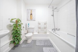 A modern bathroom with a toilet, sink, shower, and a decorative bottle painting on the wall. - Luxury Central London Balcony 1-bed Apt w/ Parking (London)
