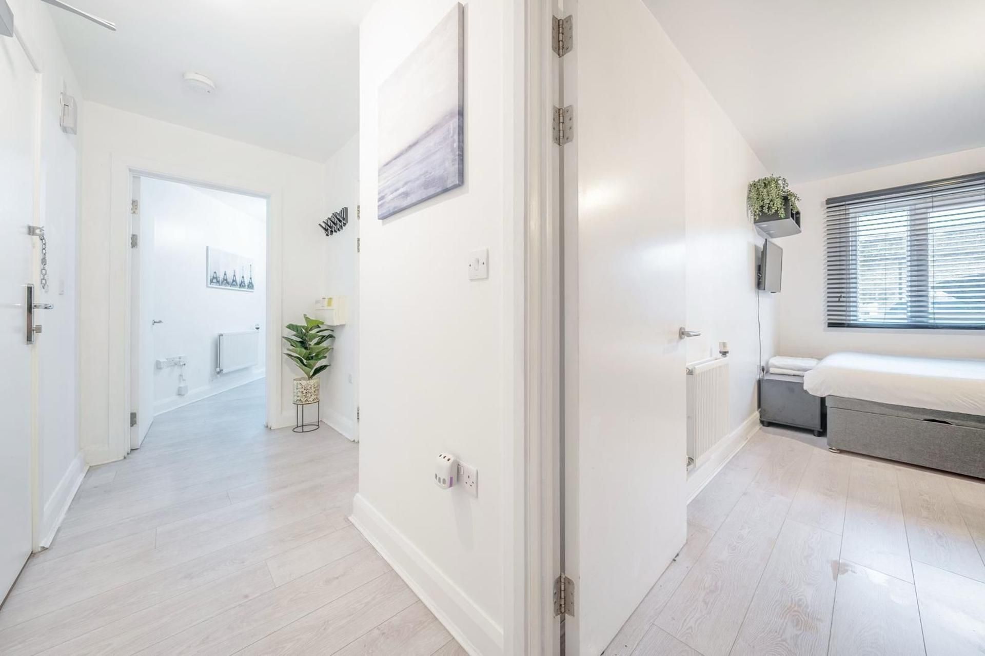 A modern interior with a hallway leading to a bedroom, a radiator, and a window with blinds.
