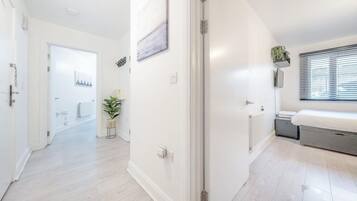 A modern interior with a hallway leading to a bedroom, a radiator, and a window with blinds.