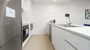 A modern kitchen with a stainless steel refrigerator, built-in oven, and dishwasher. - Convenient City Apartment in the Heart of Braddon (Braddon)
