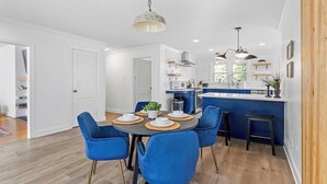 A modern kitchen with white subway tiles, blue bar stools, and a central island. - Relax In Raleigh - Room for Friends & Family! (Raleigh)