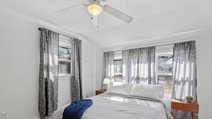 A bedroom with a bed, two nightstands, a ceiling fan, and a window with curtains. - Relax In Raleigh - Room for Friends & Family! (Raleigh)