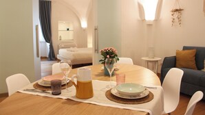A dining area with a table set for two, a vase with flowers, and a view into a bedroom. - Charming abode in the heart of Monopoli, spacious, cozy, close to everything. (Monopoli)