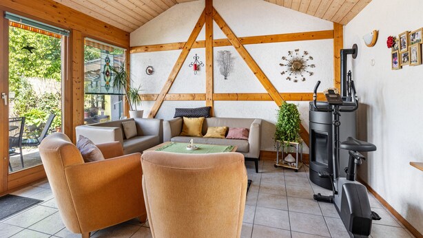 A cozy living room with a fireplace, wooden beams, and a sofa.