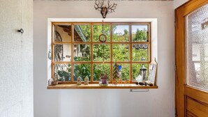 A room with a large window, wooden ceiling, and a decorative antler on the wall.
