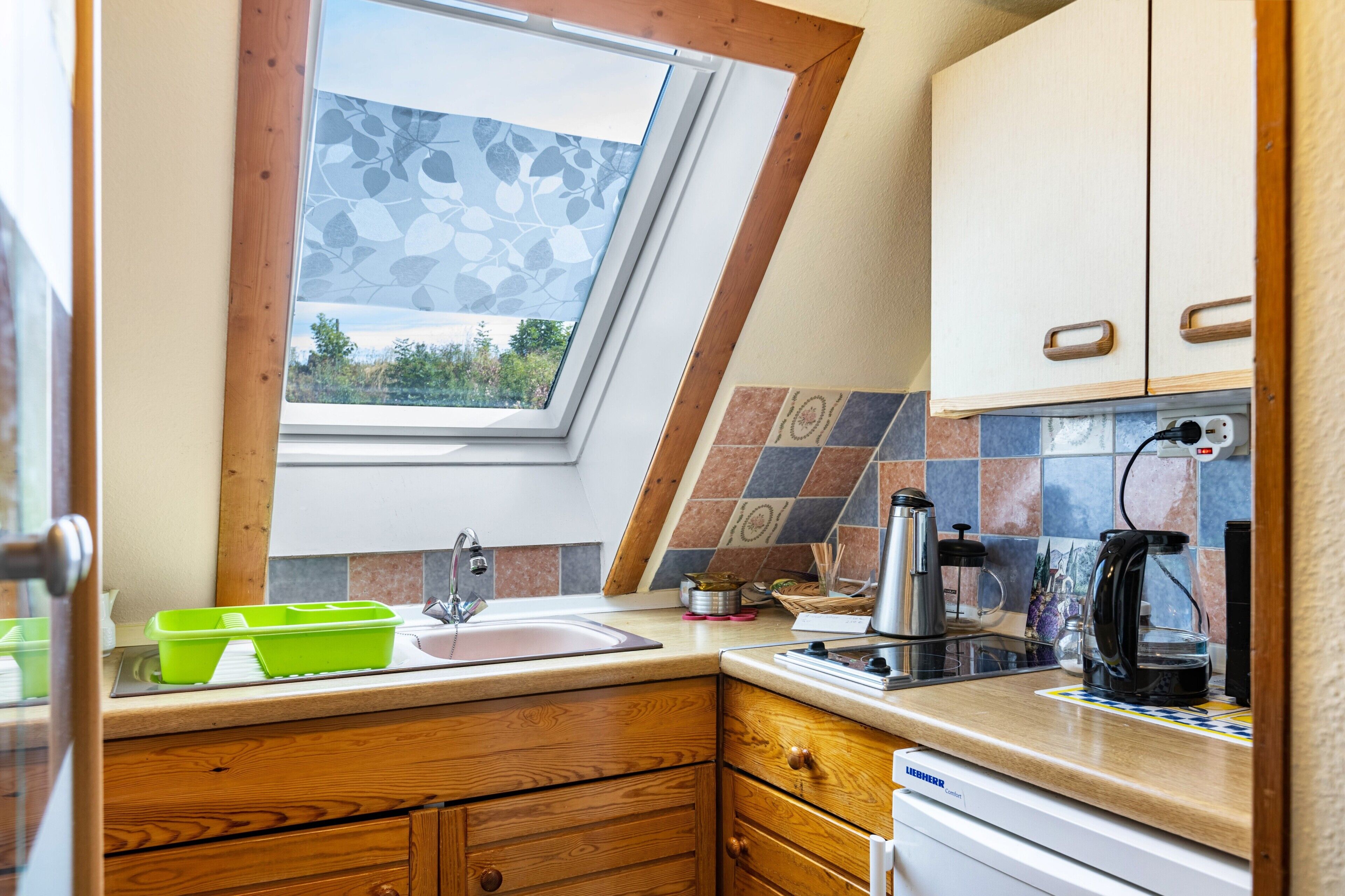 A kitchen with a window, wooden cabinets, a sink, and a coffee maker.