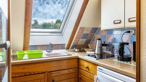 A kitchen with a window, wooden cabinets, a sink, and a coffee maker.