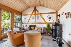 Uma sala de estar aconchegante, com lareira, vigas de madeira e um sofá.