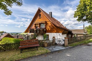 Ein Holzhaus mit Balkon, Bank und Zaun.