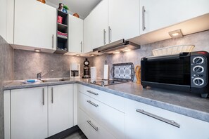 Eine moderne Küche mit weißen Schränken, eingebautem Toaster und Spüle.