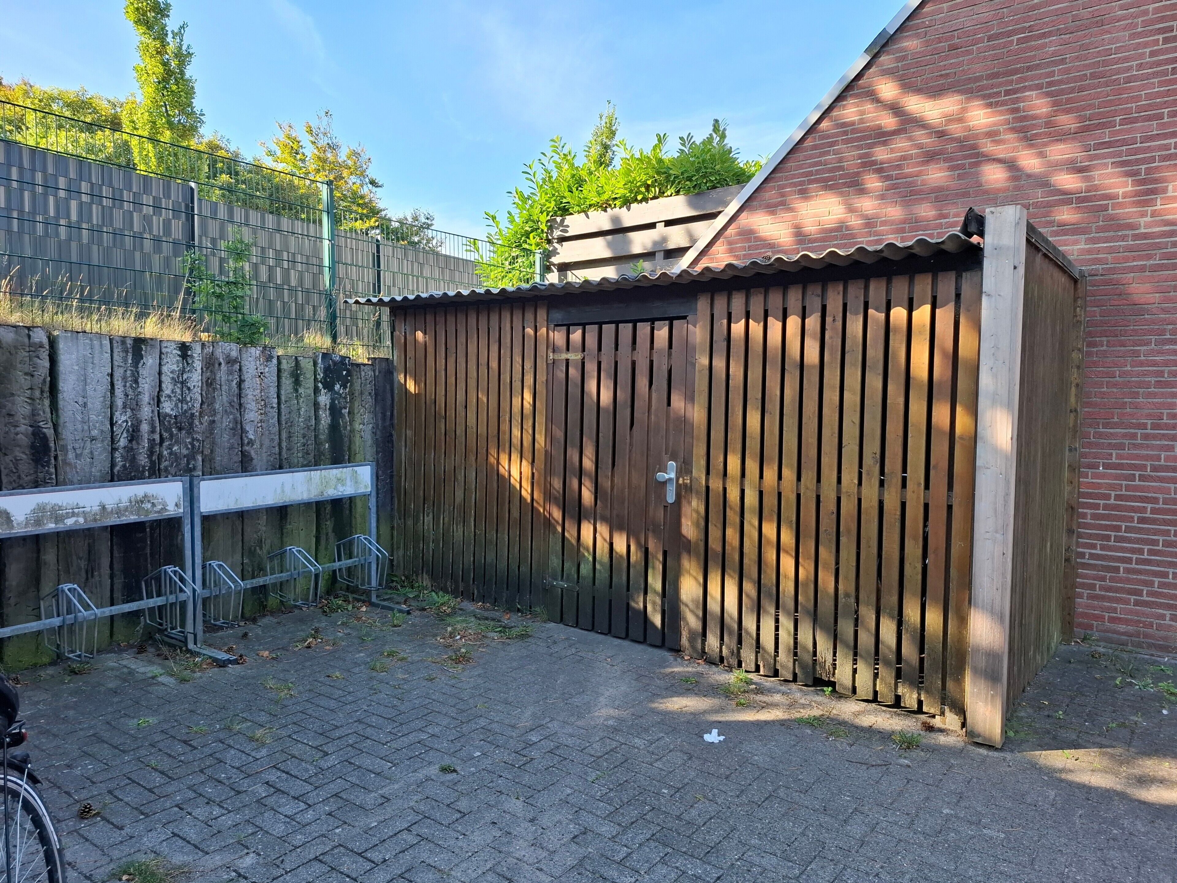 En träport, en byggnad av tegel och ett staket av metall.
