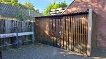 En träport, en byggnad av tegel och ett staket av metall.
