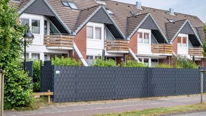 Een rij moderne herenhuisjes met zadeldaken en balkons, voorzien van een zwarte hekwerk.