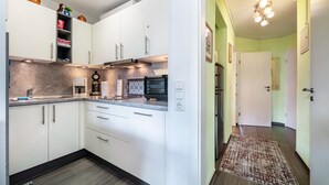 Een moderne keuken met witte kasten, een ingebouwde oven en een aanrecht met diverse apparaten.
