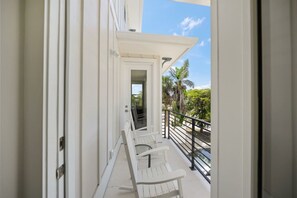 Un balcón con sillas blancas y vistas a palmeras.