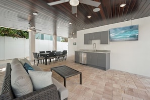 An outdoor patio with a dining area, a kitchen, and a seating area with a sofa and coffee table. - Luxury 6 Bedroom near the Village (Siesta Key)