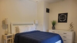 Quarto bem organizado com cama, mesas de cabeceira, cômoda e um enfeite de parede.